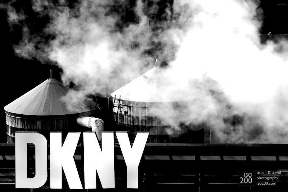Rooftop DKNY sign, with water towers and steam. Classic Manhattan skyline.