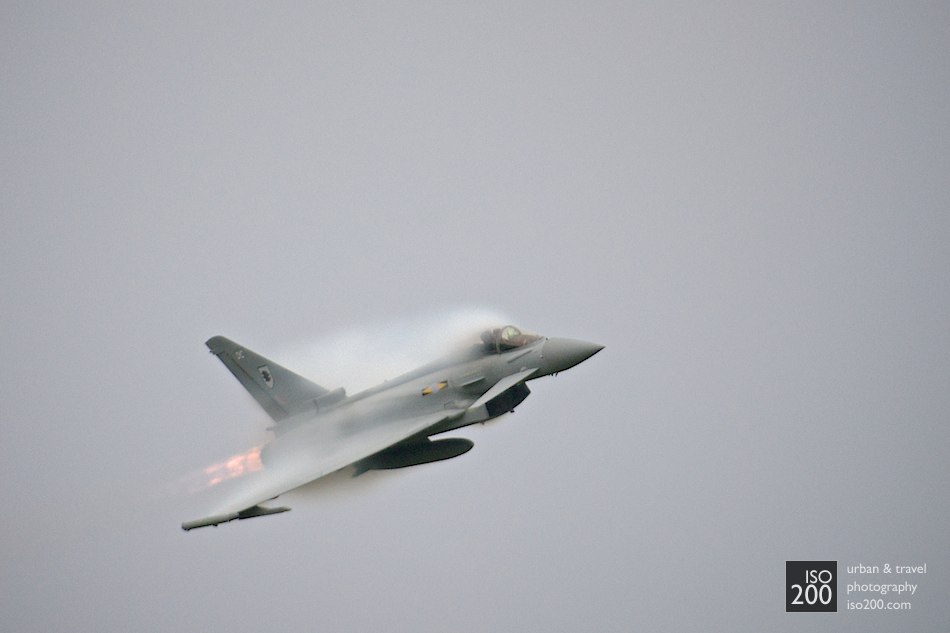 
Condensation forms around the wings and cockpit of a RAF Typhoon as it pops out of a grey and dark sky. Differences in pressure above the aeroplane at high-Gs causes a temperature drop, which causes condensation.

I hope you like aeroplanes: you might be seeing a few.