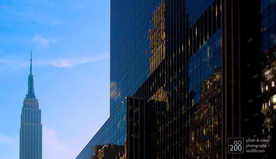 The Empire State Building in downtown Manhattan, juxtaposed against reflections from other skyscrapers against black mirrored glass, Manhattan, New York.