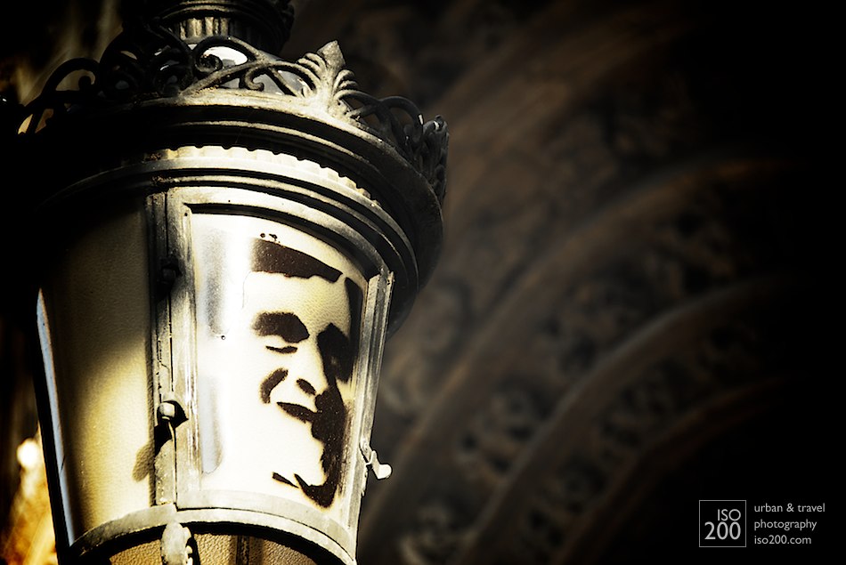 Graffiti stencil of a man's face spray painted on a city lamp outside the cathedral in Granada, Spain.